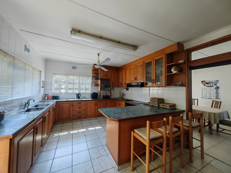A functional kitchen featuring wooden cabinetry, laminate countertops, tiled flooring, and a breakfast bar, offering a classic layout with ample storage space.