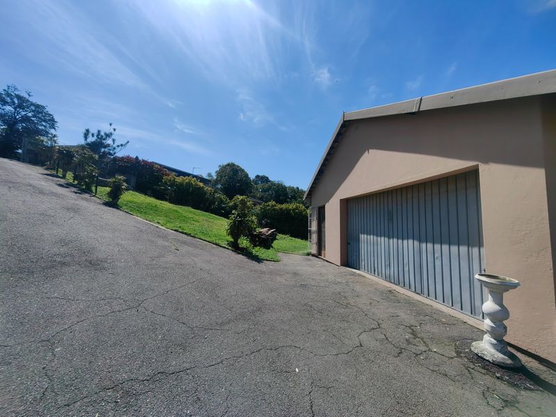 Exterior view of the property featuring a garage with a metal door and a sloped asphalt driveway with visible surface cracking.