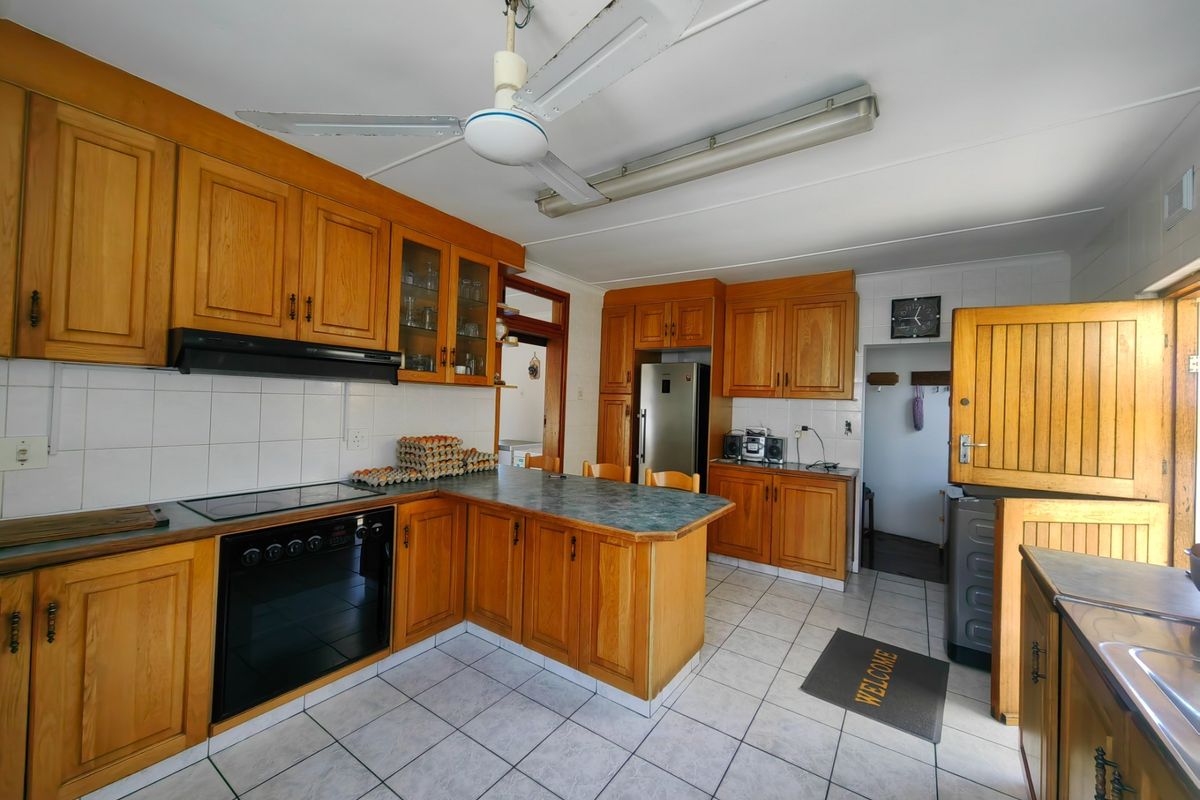 A functional kitchen featuring wooden cabinetry, tiled flooring, built-in oven and hob, and a classic stable door leading to the exterior.
