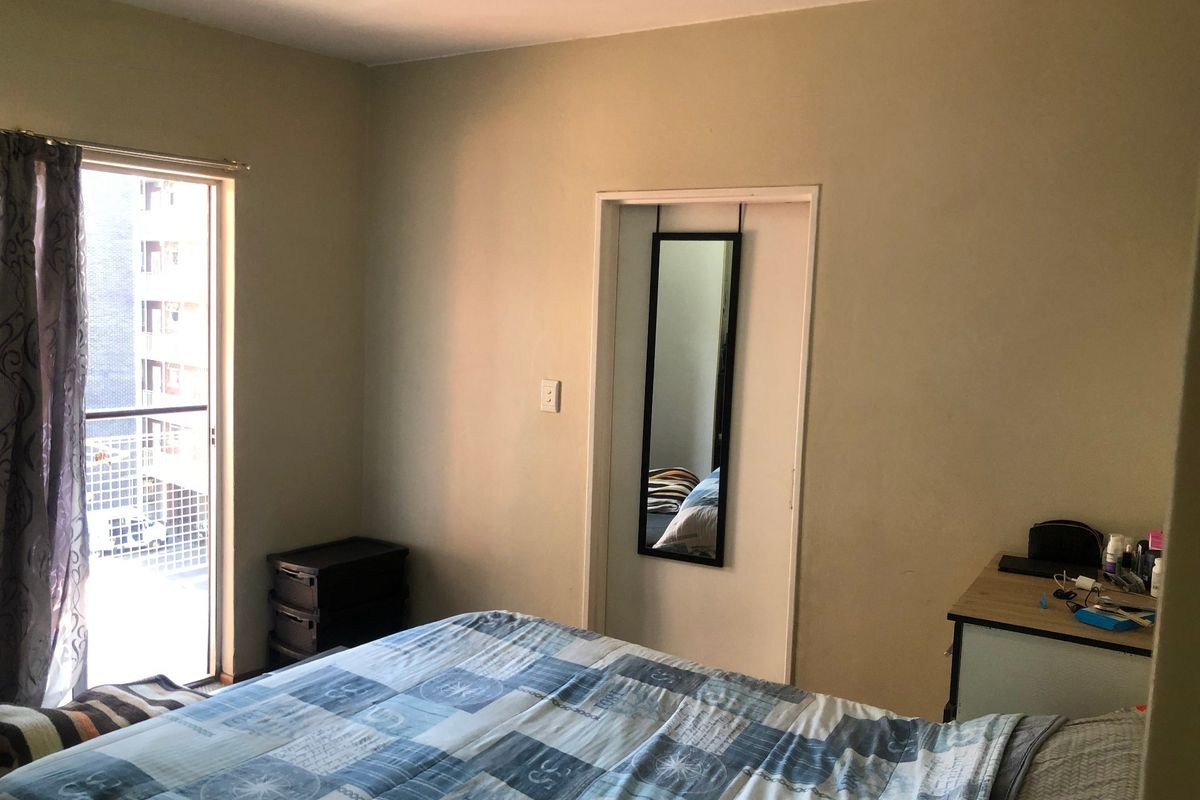 A bedroom featuring a sliding glass door providing access to a balcony, with neutral wall finishes.