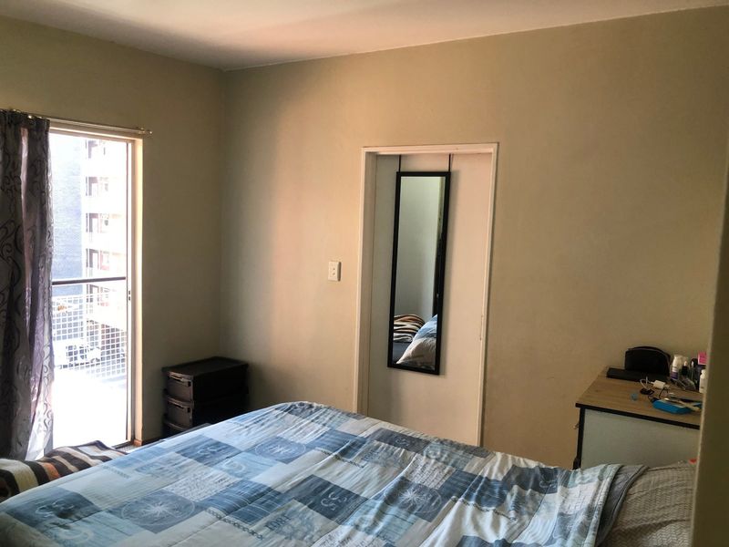 A bedroom featuring a sliding glass door providing access to a balcony, with neutral wall finishes.