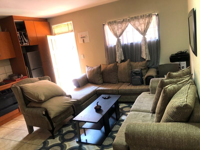 Open plan living area featuring tiled flooring and an integrated kitchen with built-in cabinetry and oven, providing a functional combined living and cooking space.