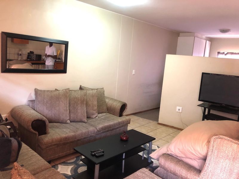 A living room area featuring tiled flooring and a partial room divider, providing a functional layout for the apartment.