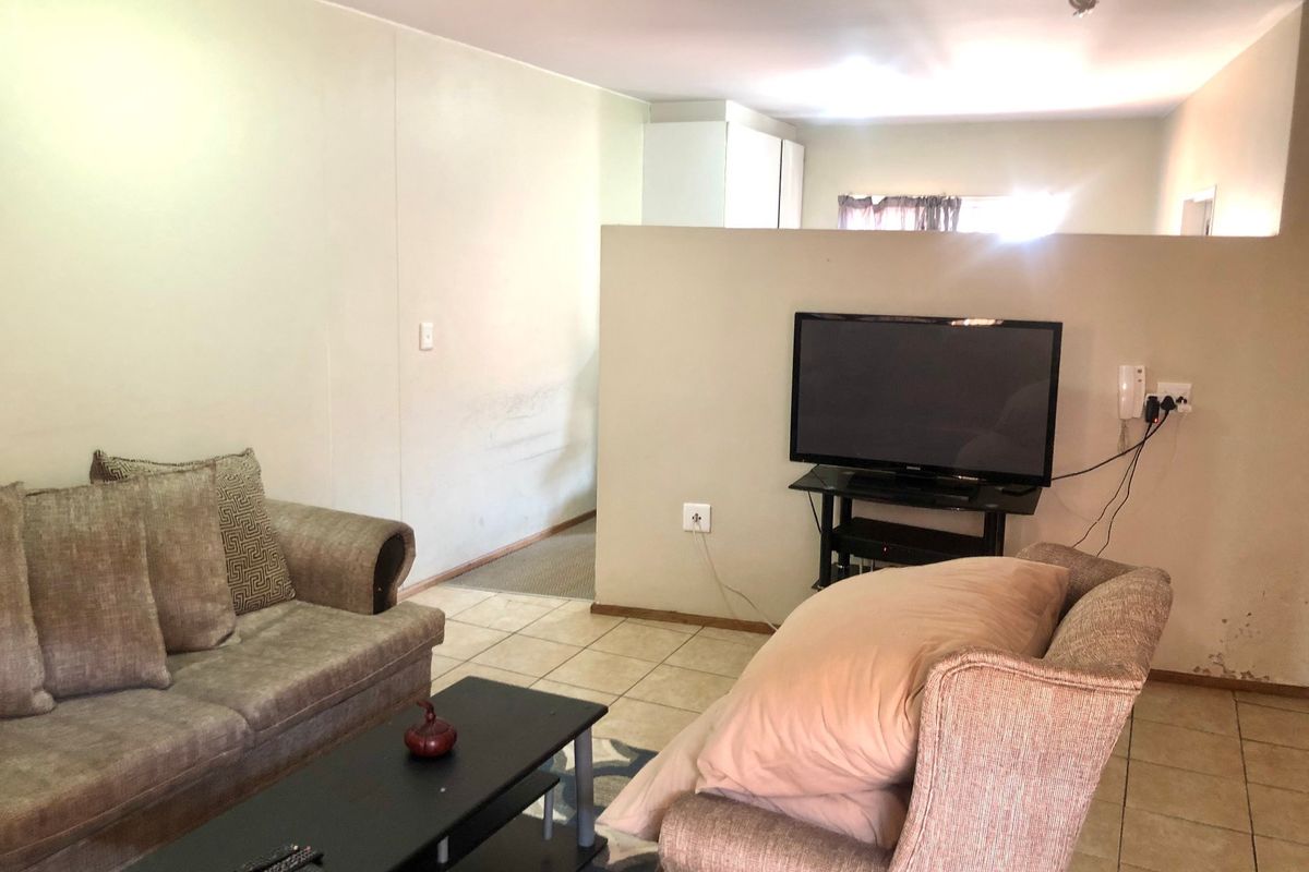 A living area featuring tiled flooring and a partial room divider, providing a functional layout with potential for cosmetic updates.