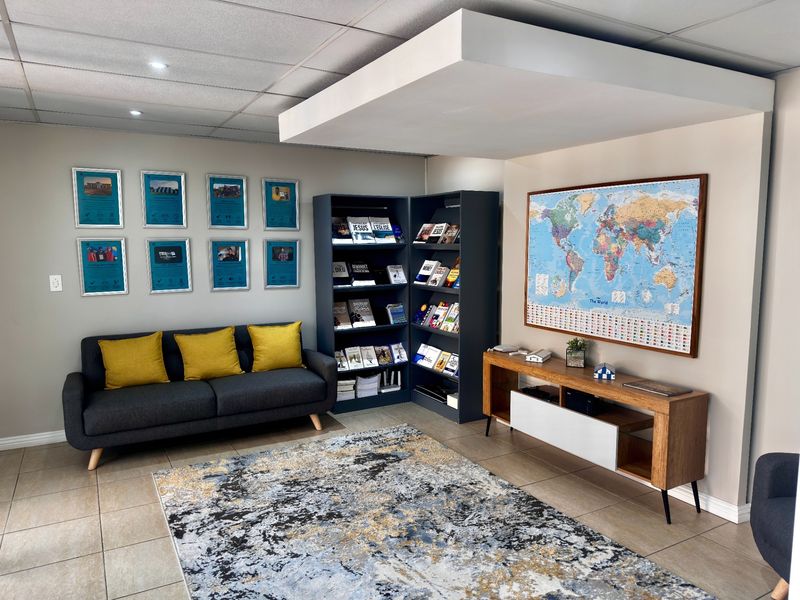 A well-maintained office reception or waiting area featuring tiled flooring, a suspended ceiling with recessed lighting, and a modern bulkhead architectural detail.