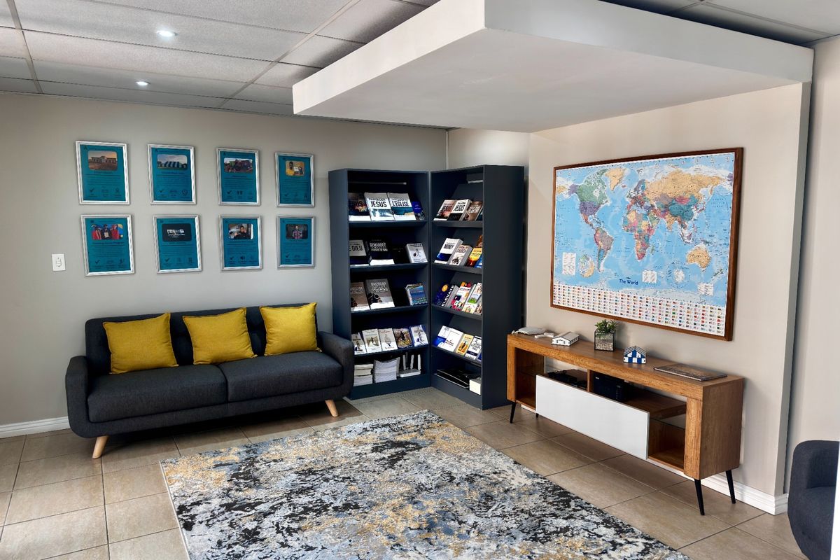 A well-maintained office reception or waiting area featuring tiled flooring, a suspended ceiling with recessed lighting, and a modern bulkhead architectural detail.