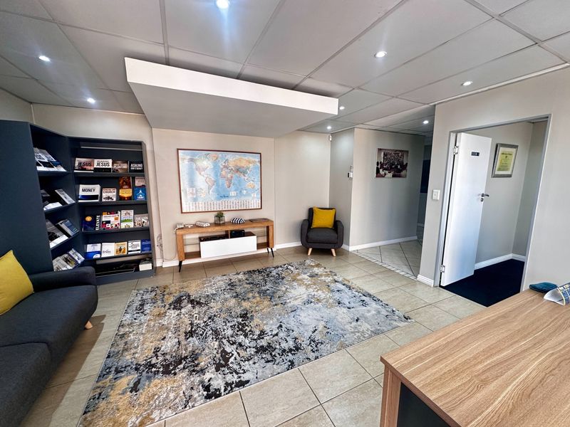 A well-maintained office reception area featuring tiled flooring, a suspended ceiling with recessed lighting, and a built-in shelving unit.