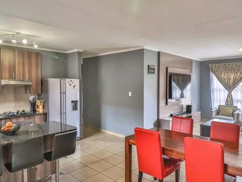 Spacious open-plan living area featuring a modern kitchen with granite countertops, gas hob, and a dedicated built-in media wall in the lounge.