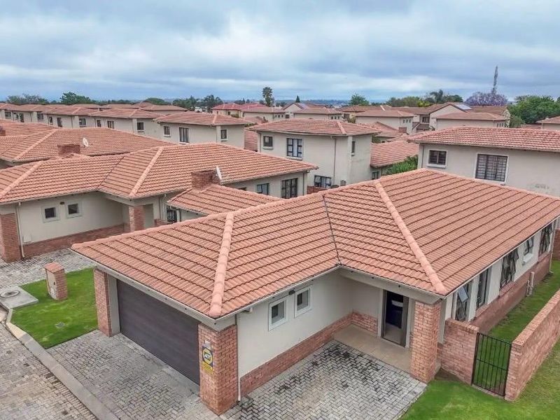 Aerial view of a residential estate featuring multiple houses with tiled roofs, paved driveways, and private garden areas.