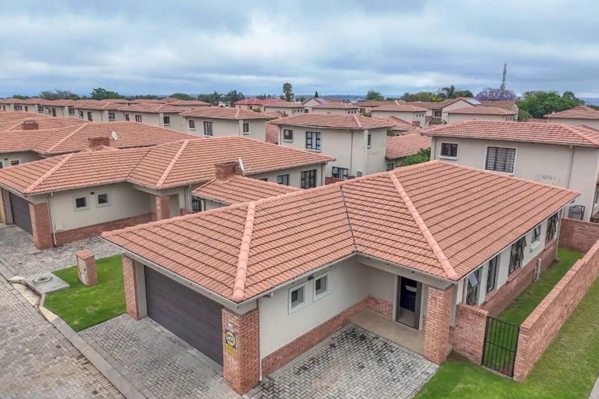 Aerial view of a residential estate featuring multiple houses with tiled roofs, paved driveways, and private garden areas.