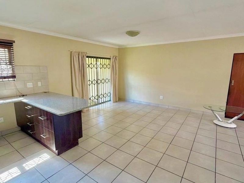 Spacious open-plan living area featuring tiled flooring, a functional kitchen with stone countertops, and sliding glass doors leading to the exterior.