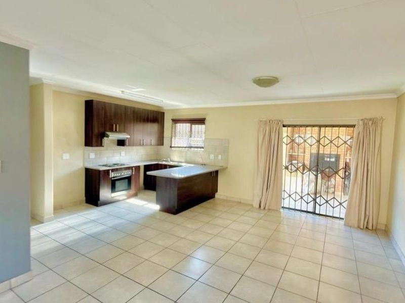 Spacious open-plan living area featuring a functional kitchen with built-in cabinetry, oven, and hob, leading out to a patio through sliding glass doors.