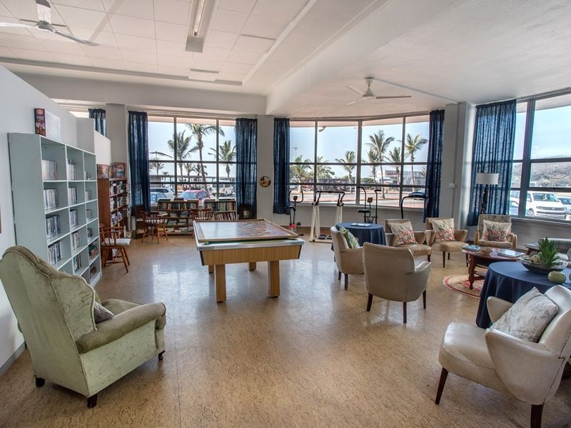 Spacious communal clubhouse area featuring extensive floor-to-ceiling windows, cork flooring, and ceiling fans, providing a bright and versatile social space for residents.