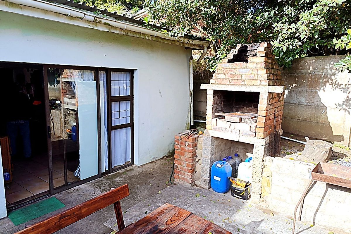 Outdoor patio area featuring a built-in brick braai, concrete flooring, and direct access to the interior via a sliding glass door.