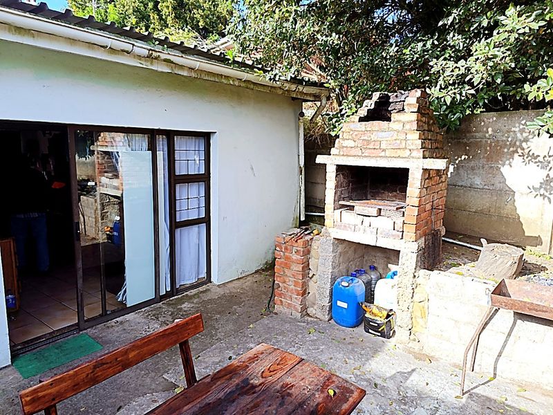 Outdoor patio area featuring a built-in brick braai, concrete flooring, and direct access to the interior via a sliding glass door.