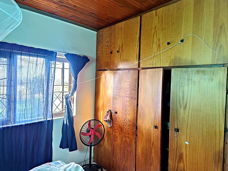 Bedroom featuring built-in wooden cupboards and a timber ceiling, with security burglar bars installed on the window.