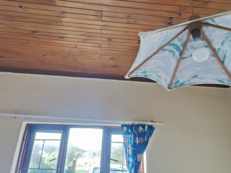 A bedroom featuring a timber tongue and groove ceiling, steel window frames with security bars, and visible hairline wall cracks.