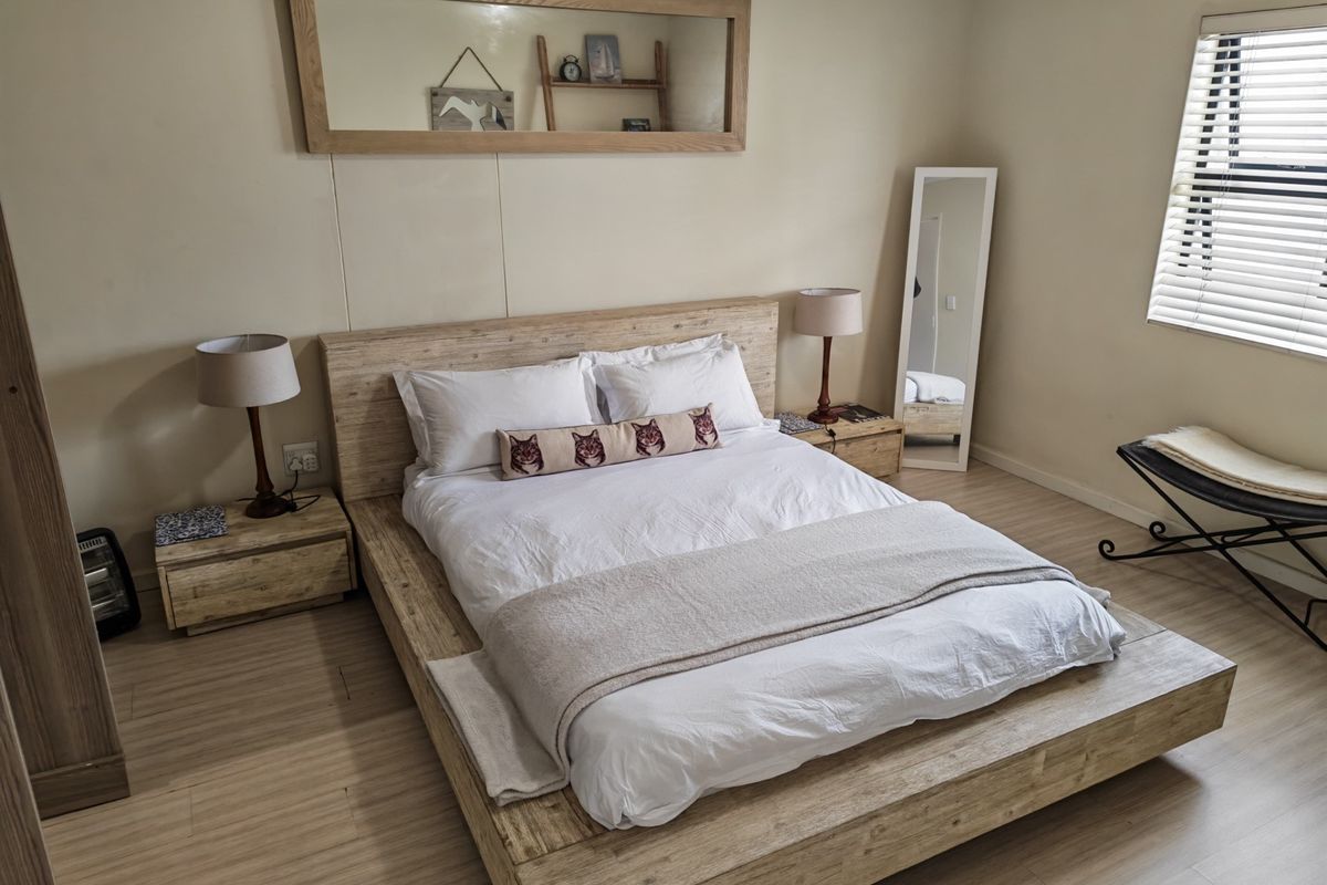 A well-maintained bedroom featuring light wood-look laminate flooring and venetian blinds, providing a neutral and comfortable living space.