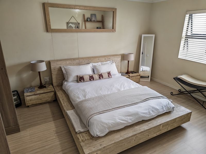 A well-maintained bedroom featuring light wood-look laminate flooring and venetian blinds, providing a neutral and comfortable living space.