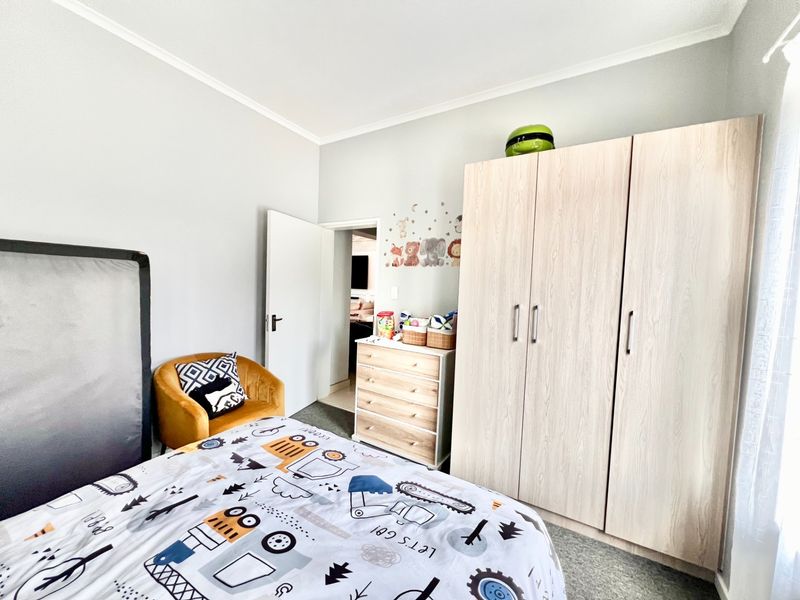 A well-maintained bedroom featuring a large built-in wardrobe with light wood-grain finish and neutral wall tones.