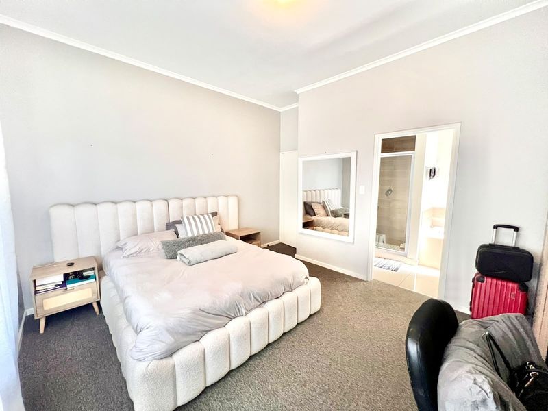 Spacious bedroom featuring neutral carpeting, cove ceiling detailing, and direct access to an en-suite bathroom with a shower.