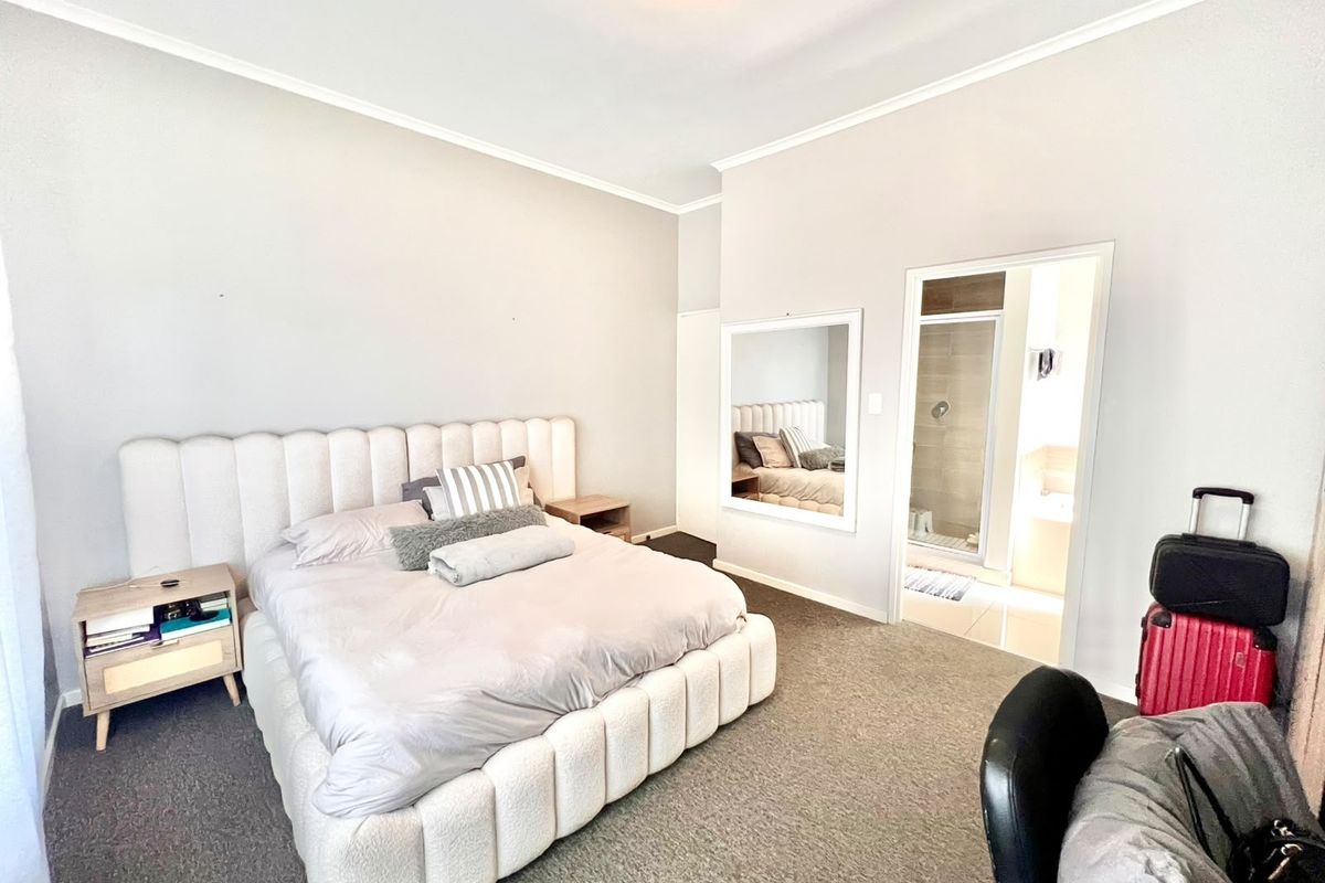 Spacious bedroom featuring neutral carpeting, cove ceiling detailing, and direct access to an en-suite bathroom with a shower.