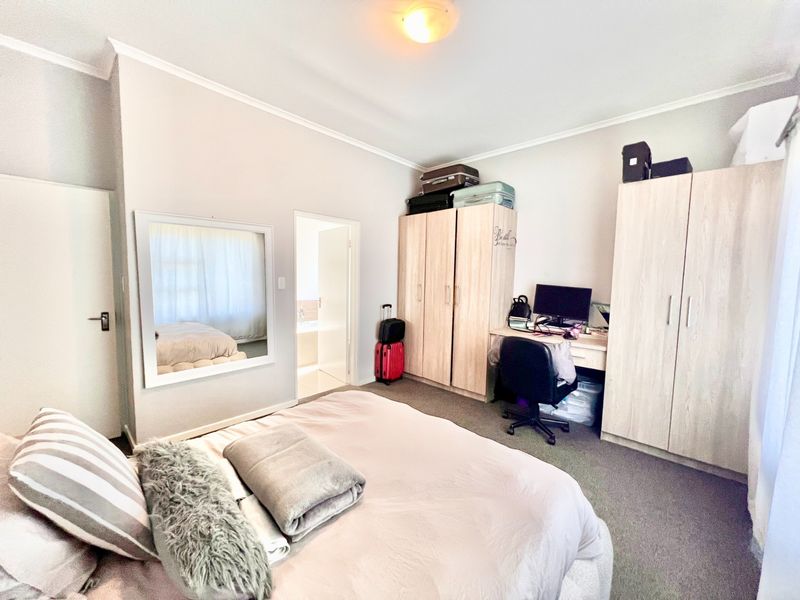 A functional bedroom featuring built-in cupboards, carpeted flooring, and direct access to an en-suite bathroom.