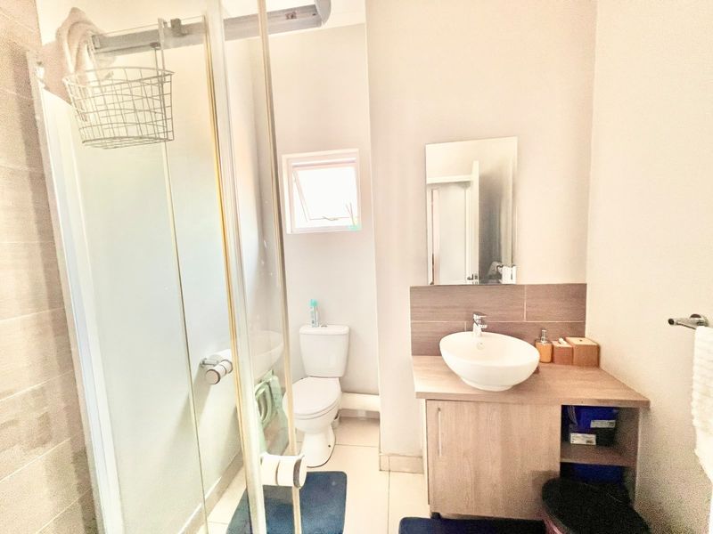 A functional bathroom featuring a glass shower enclosure, a modern vessel sink with a vanity cabinet, and a toilet.