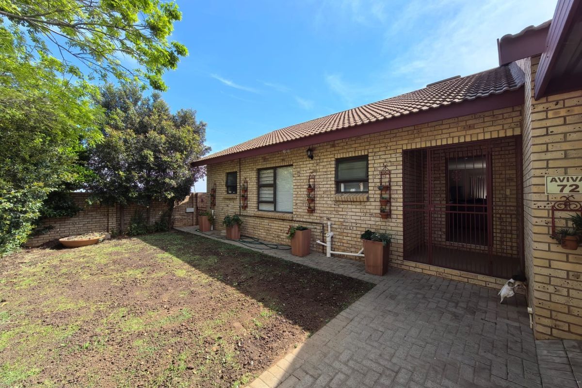 Rear view of the property featuring a face brick facade, tiled roof, paved patio area, and a private garden space.