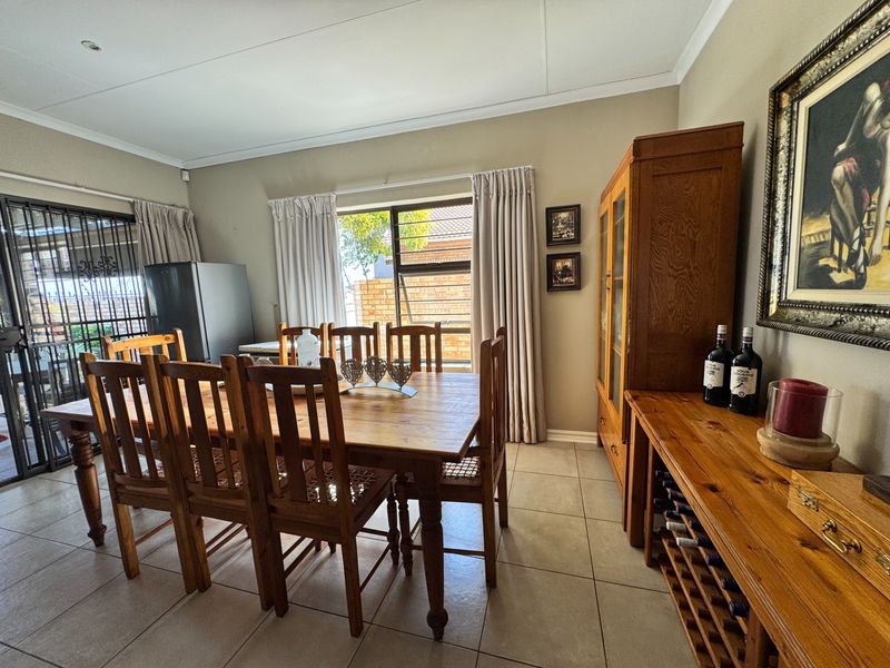 A dining room featuring tiled flooring, neutral wall tones, and a security gate leading to the exterior.