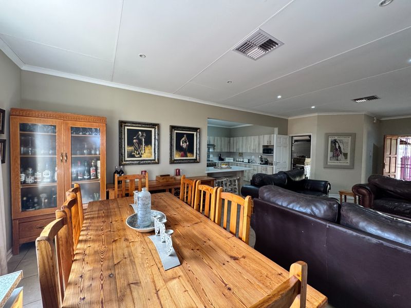 Spacious open-plan living and dining area featuring recessed lighting, ducted air conditioning, and a functional kitchen with island bench.