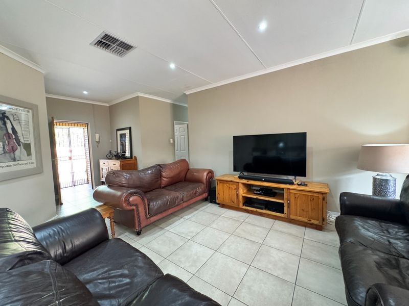 A spacious living room featuring neutral wall tones, tiled flooring, and recessed lighting, providing a comfortable and functional area for relaxation.