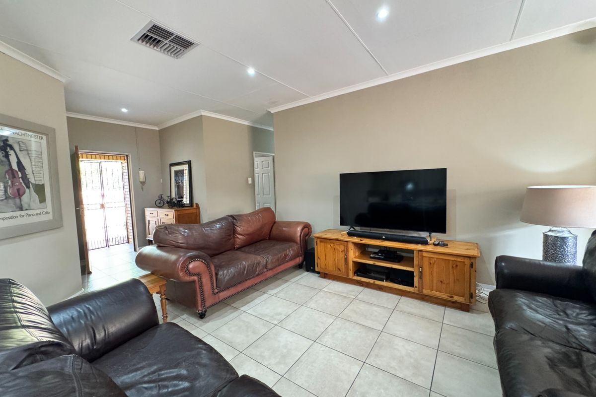 A spacious living room featuring neutral wall tones, tiled flooring, and recessed lighting, providing a comfortable and functional area for relaxation.