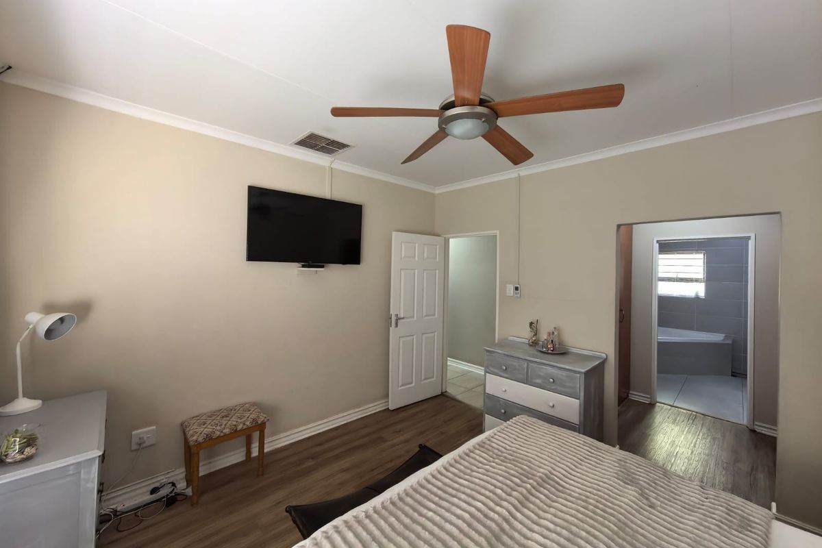 A bedroom featuring laminate flooring, a ceiling fan, and direct access to an en-suite bathroom.