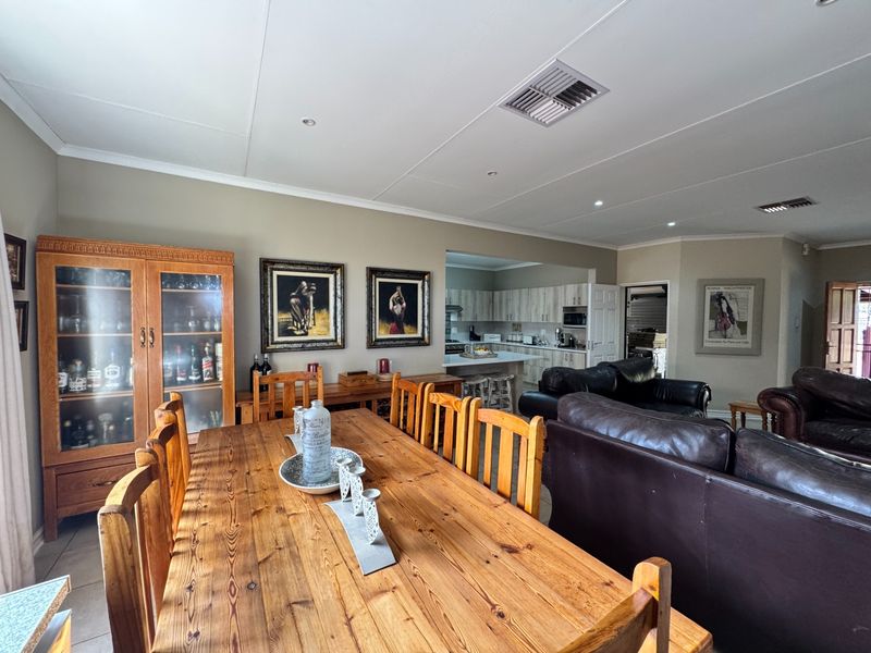 Spacious open-plan living and dining area featuring a connected kitchen with built-in cabinetry and modern ducted air conditioning.