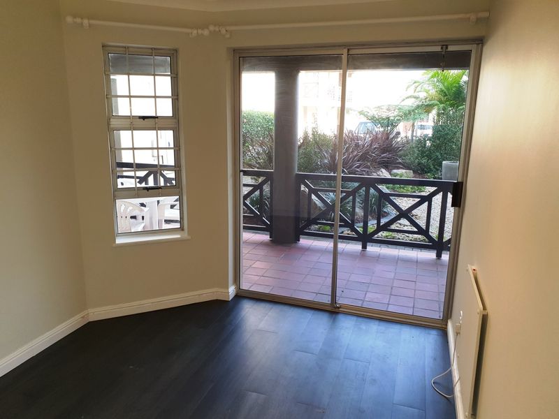 Bright living area featuring dark laminate flooring, a wall-mounted heater, and sliding glass doors providing direct access to a private patio.
