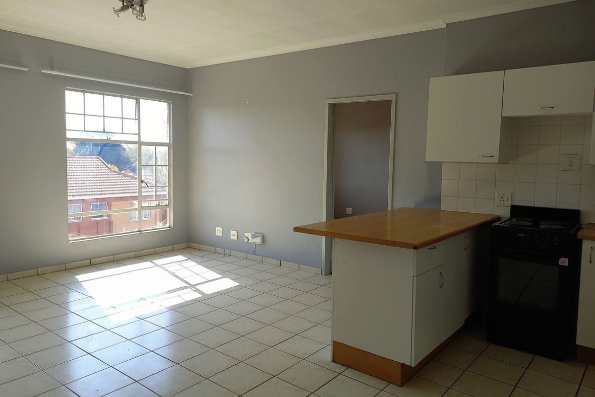 Open-plan living and kitchen area featuring tiled flooring, built-in cabinetry, and a breakfast counter, offering a functional and bright space.