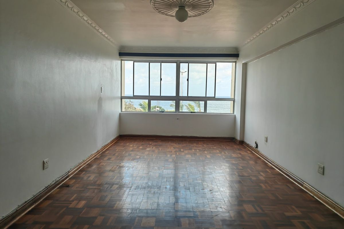 An empty living room featuring original parquet flooring, decorative ceiling rose, and large windows offering ocean views.
