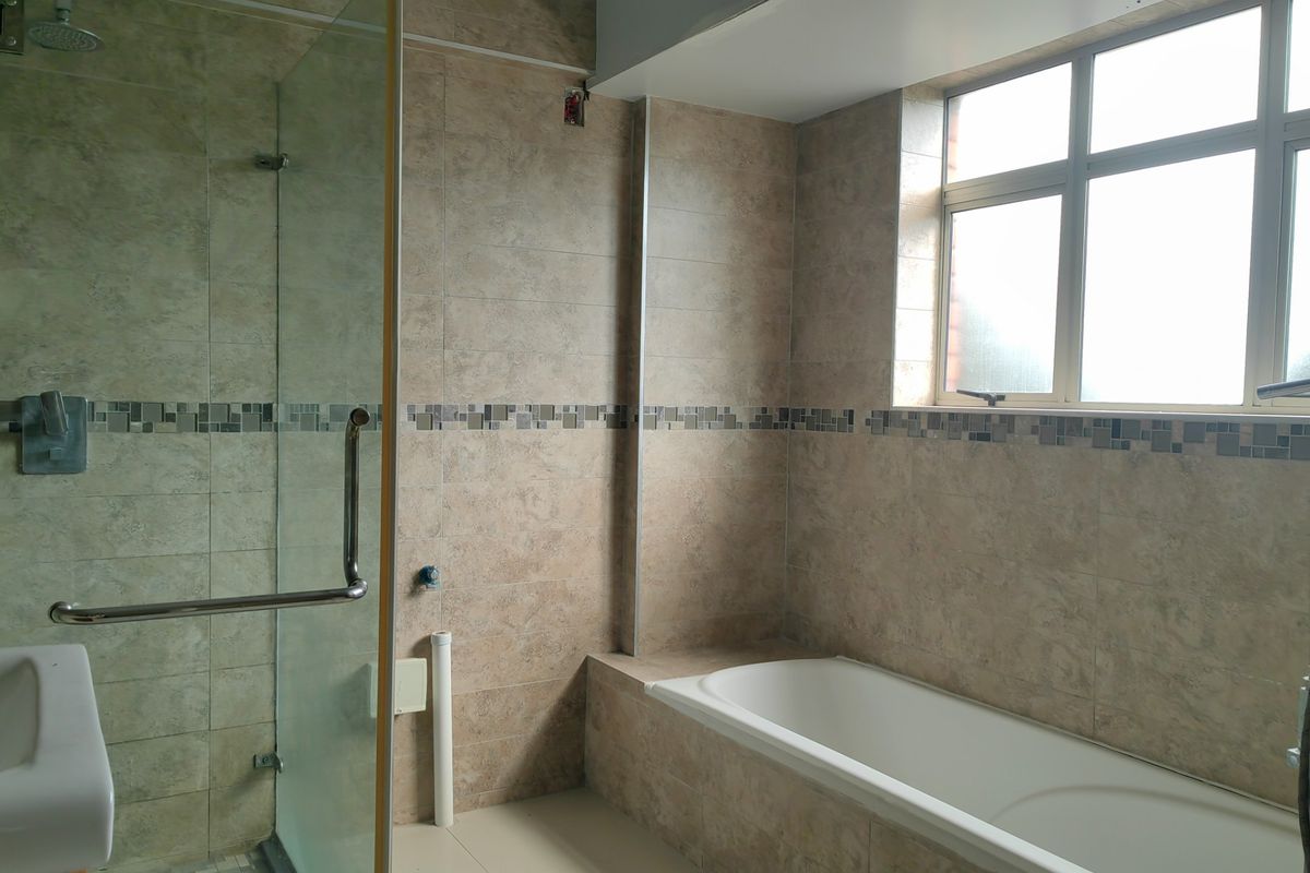 A bathroom featuring a built-in bathtub, a glass-enclosed shower, and neutral wall tiling. The space is vacant and ready for finishing touches.