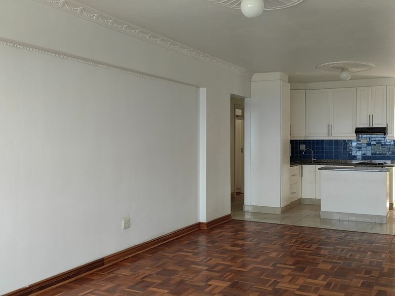 Open plan living area featuring classic parquet flooring, decorative crown molding, and a functional kitchen with granite countertops and tiled backsplash.
