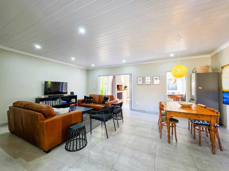 Spacious open-plan living and dining area featuring modern tiled flooring, recessed downlighting, and a clean tongue and groove ceiling design.