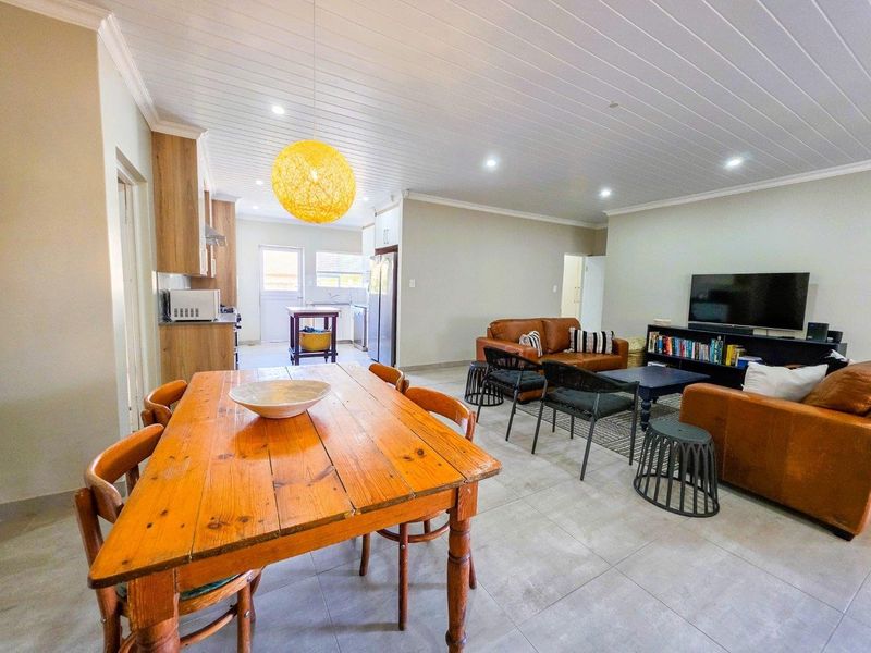 Spacious open-plan living, dining, and kitchen area featuring tiled floors, timber cabinetry, and a distinctive tongue and groove ceiling with recessed lighting.