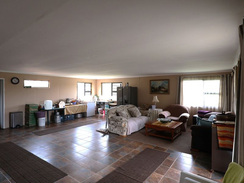 Spacious open-plan living area featuring tiled flooring and multiple windows, offering a versatile layout for combined lounge and dining arrangements.