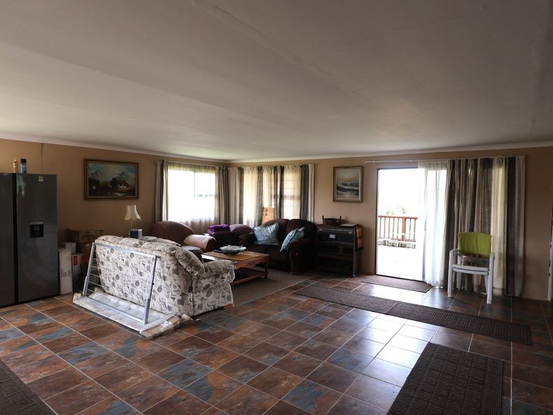 Spacious open-plan living area featuring tiled flooring and direct access to an outdoor patio through a sliding glass door.