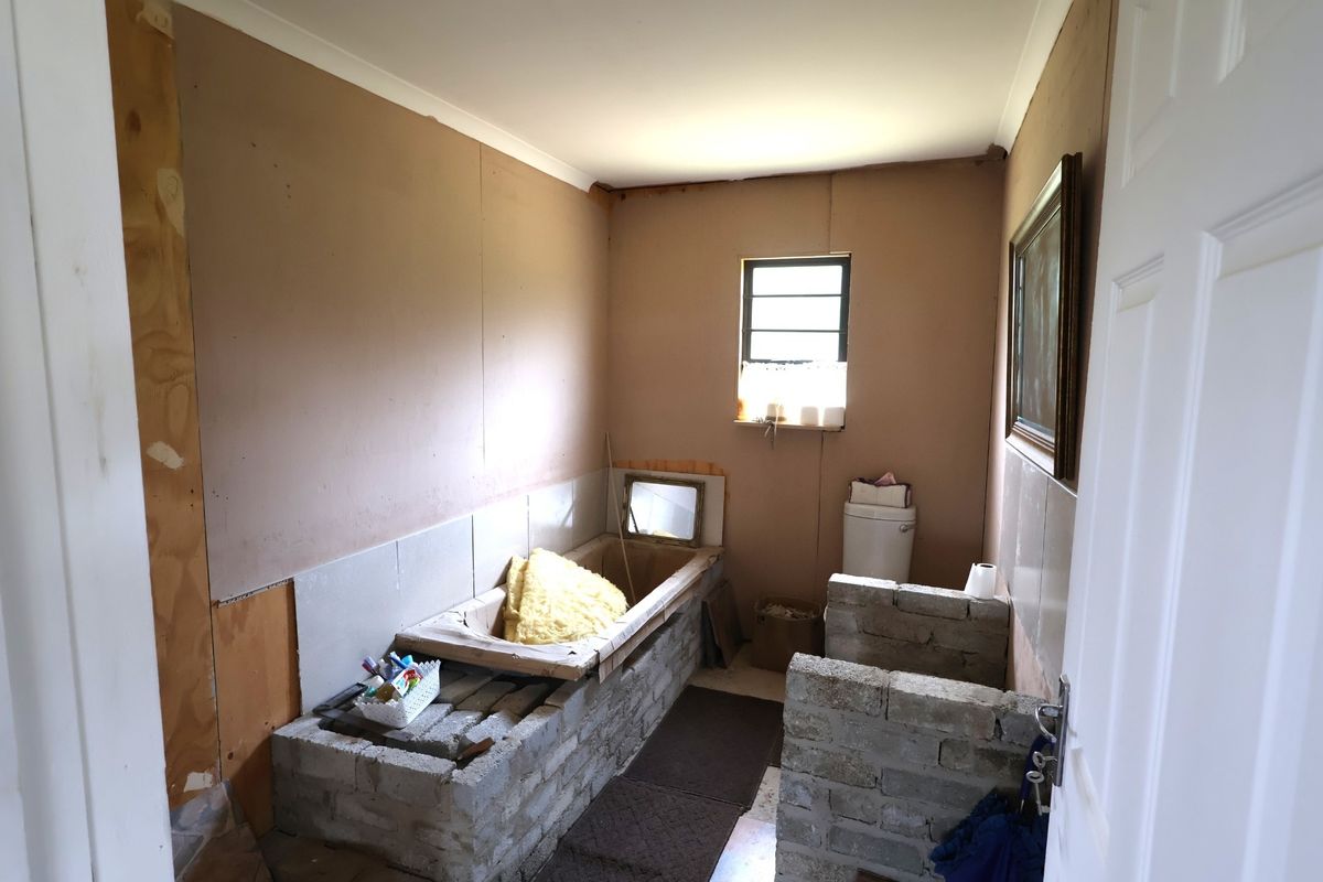 A bathroom currently undergoing renovation, featuring exposed brickwork, unfinished wall surfaces, and basic plumbing fixtures ready for completion.
