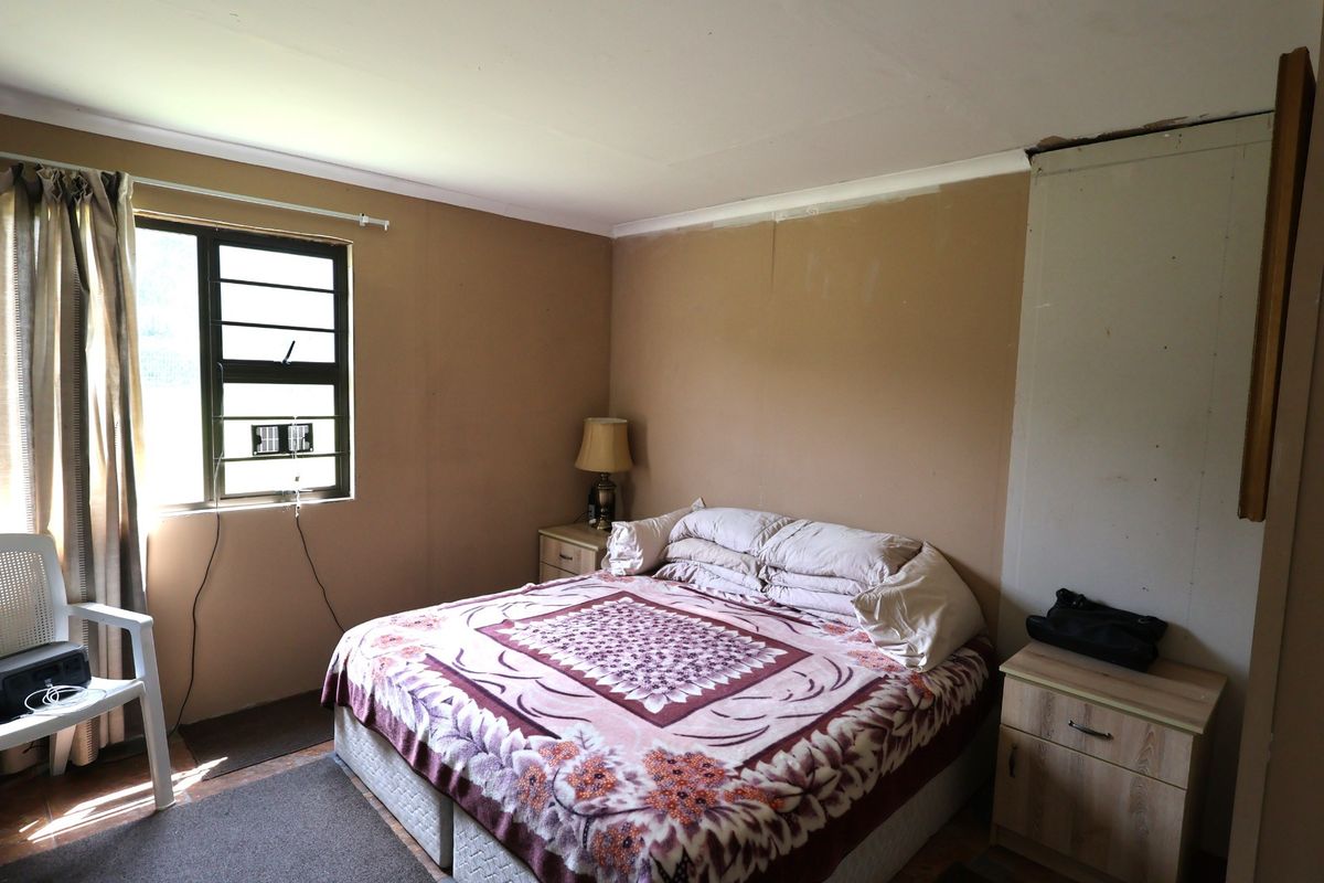 A bedroom featuring louvered windows and coving, currently requiring cosmetic attention to wall finishes and paintwork.