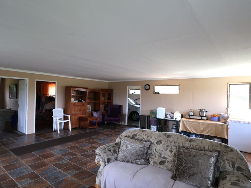 Spacious open-plan living area featuring tiled flooring and multiple access points to adjacent rooms, offering a versatile layout for renovation.