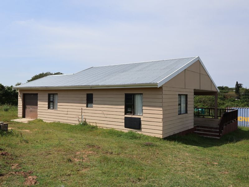 A detached house featuring timber cladding, a corrugated metal roof, an integrated garage, and a rear covered patio with a timber deck.