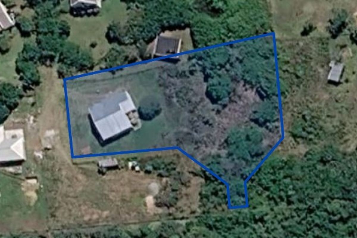 Aerial view of the property showing the residential dwelling situated on a large, partially wooded plot with defined boundary lines.
