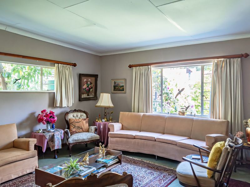 A well-lit living room featuring large windows, coved ceilings, and neutral wall tones, offering a comfortable and inviting space for relaxation.